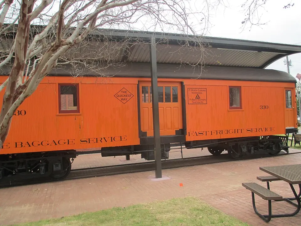 Vintage orange interurban railcar marked Fort Worth Southern Traction Co. on a brick plaza in Burleson, TX
